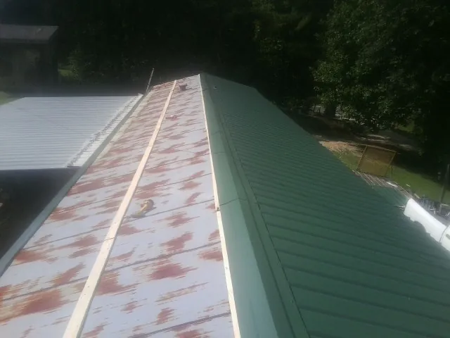 Old rusted panels beside newly installed green metal roofing — Wind Damage Roof Repair by Roofing Brothers in Arnoldsburg