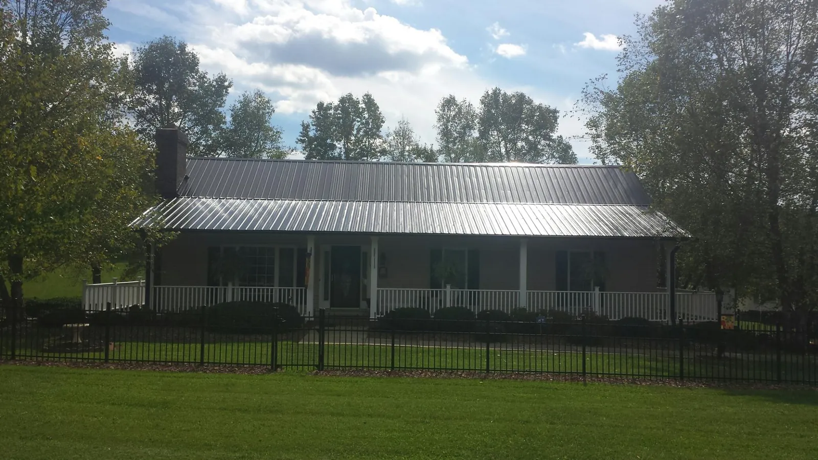 Gray metal roof on a brick ranch with a full width front porch — Gutter Guard Installation work by our crew in Arnoldsburg