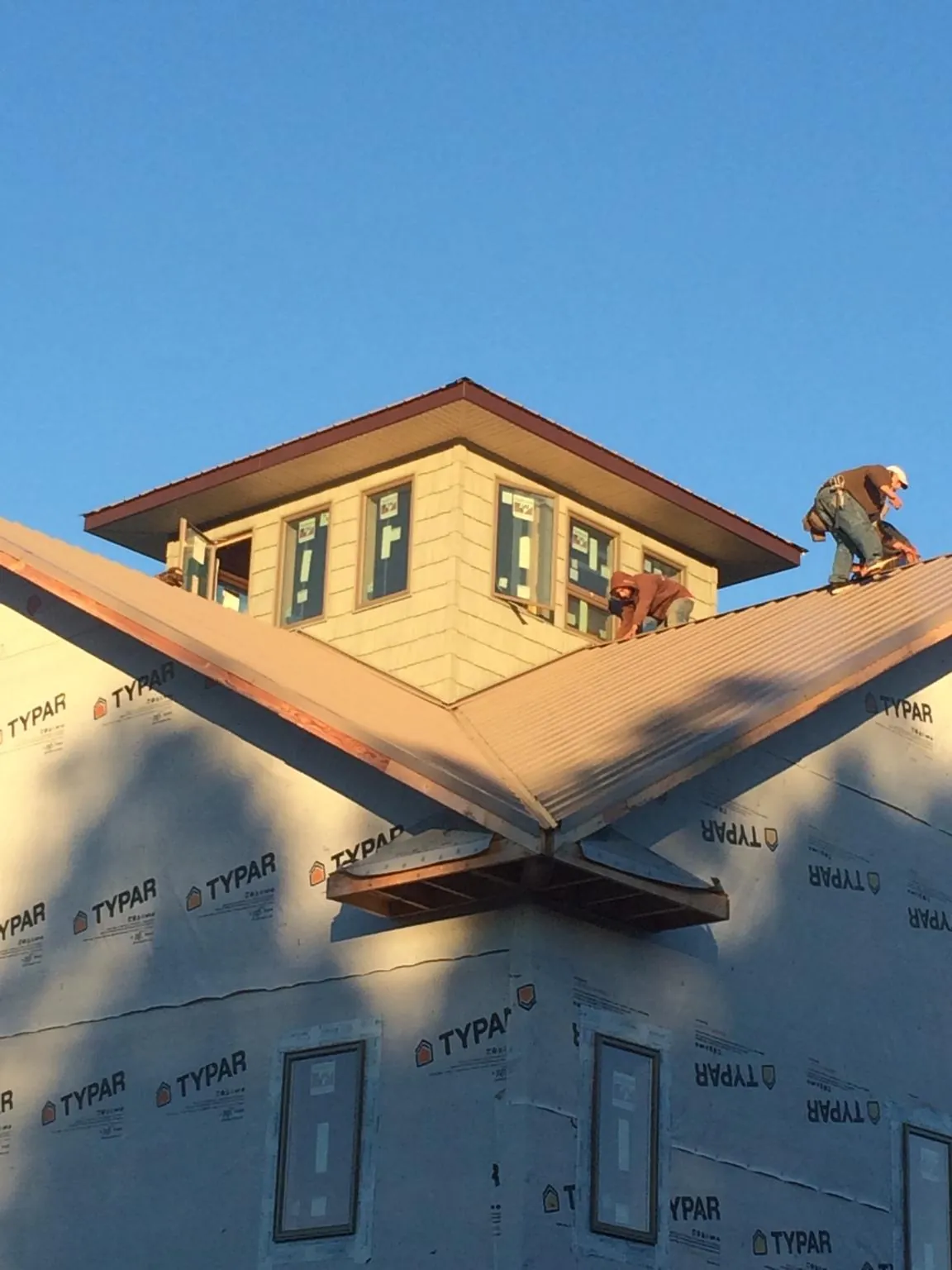 Roofers working around a rooftop cupola on a new metal roof at sunset — Roof Waterproofing in Arnoldsburg by Roofing Brothers